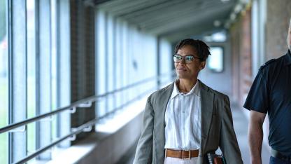 Zwei Personen gehen durch einen Flur, eine trägt ein Namensschild mit